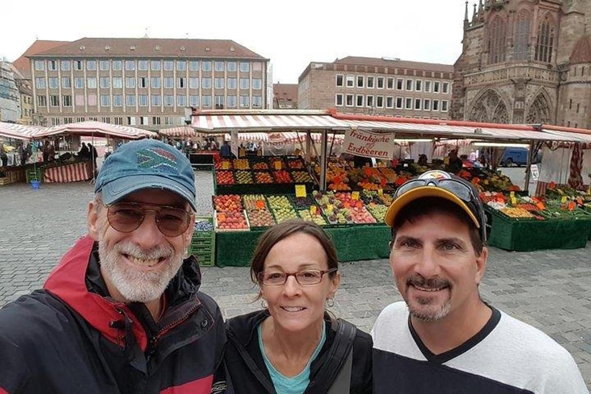 due uomini e una donna in piedi davanti a un mercato