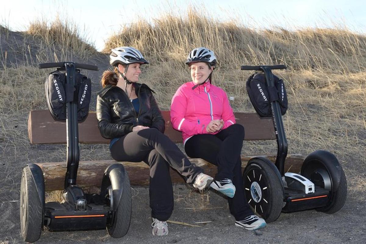 due donne che indossano caschi sedute su una panchina con i segway