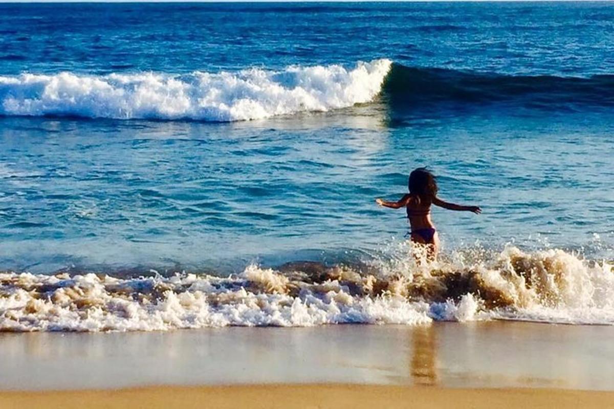 seorang gadis muda bermain air di pantai