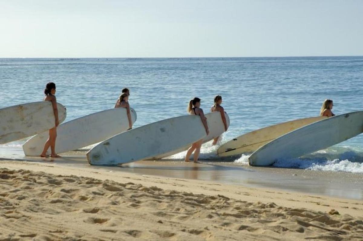 a group of surfers walking on the beach with their surfboards