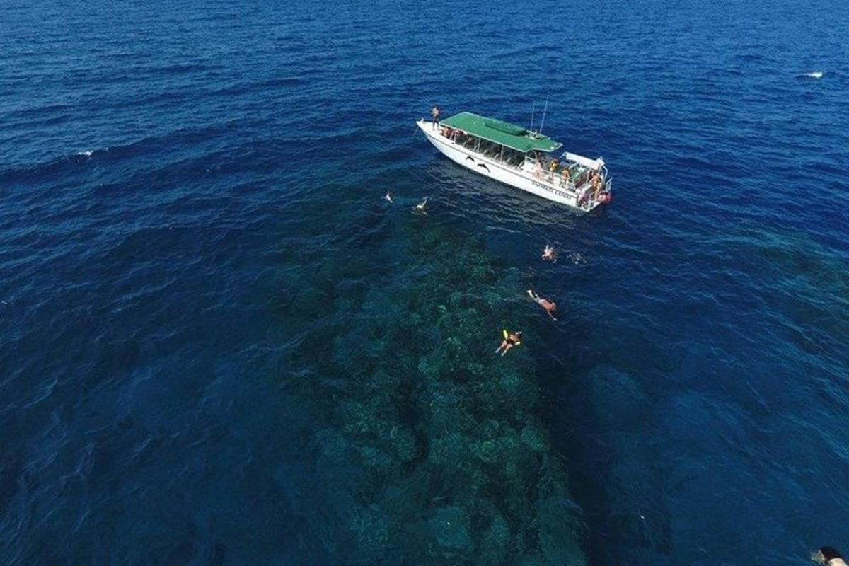 loď v oceánu s lidmi plavajícími ve vodě