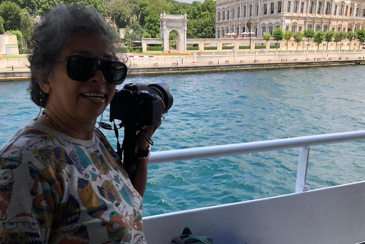 una dona amb ulleres de sol sostenint una càmera en un vaixell