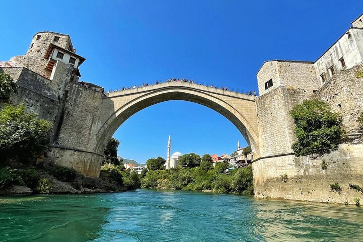 un vecchio ponte sopra un fiume con persone che camminano sotto