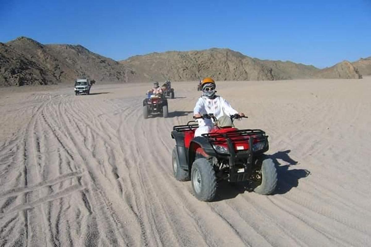 un grup de oameni care călătoresc pe ATV-uri în deșert