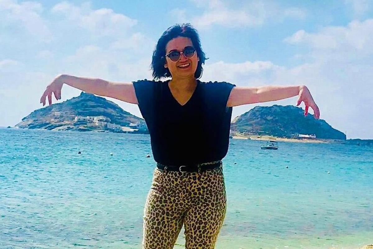 una donna in piedi sulla spiaggia con le braccia tese
