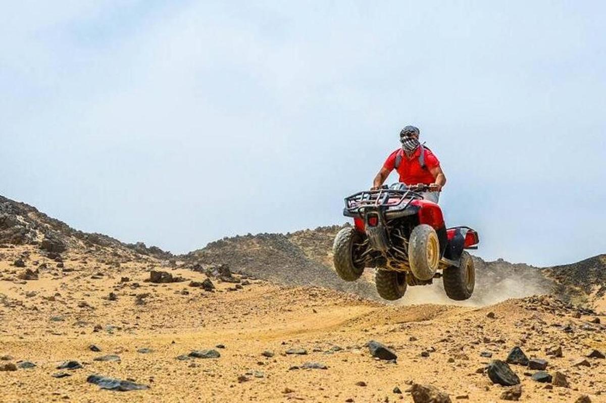 seorang lelaki menunggang basikal quad di padang pasir