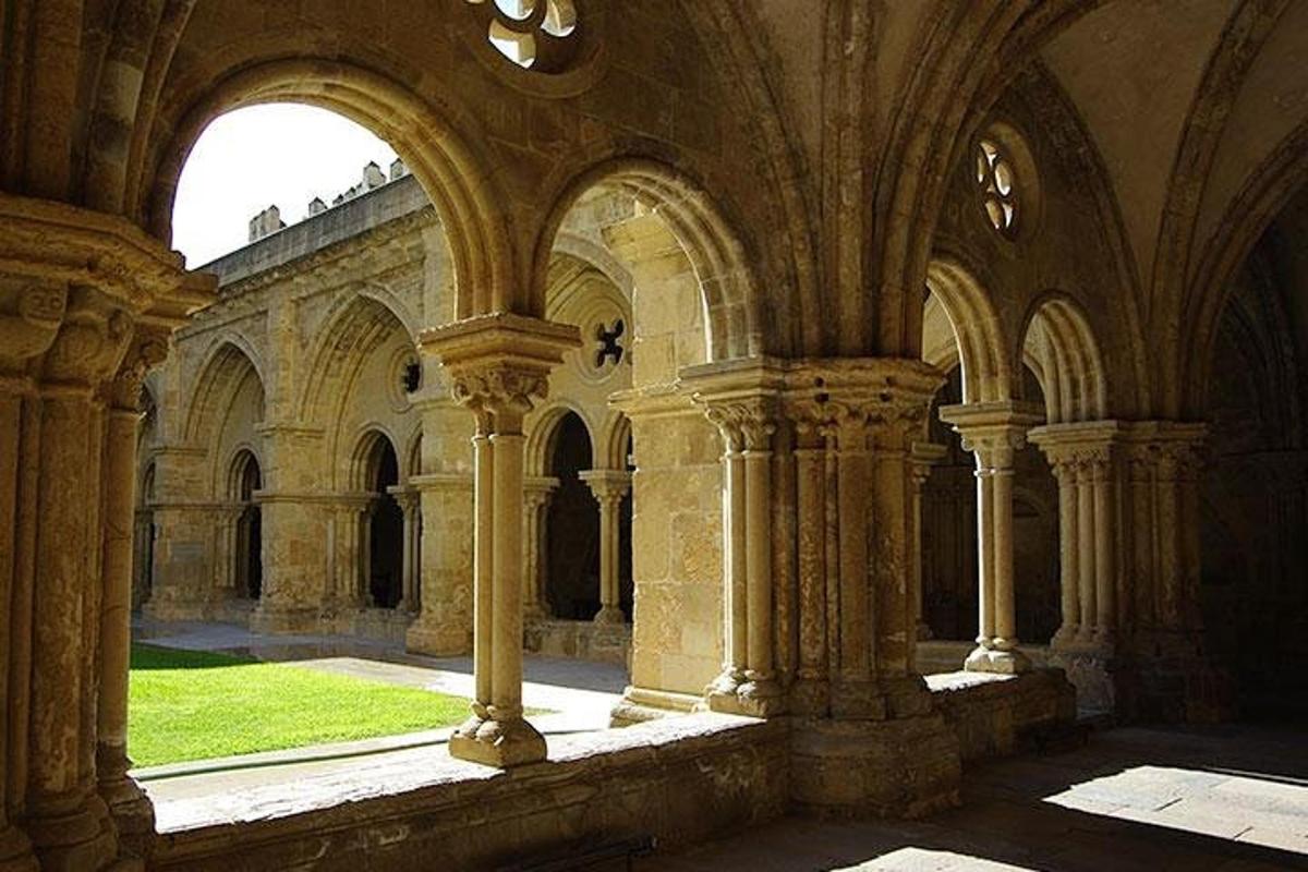 un vecchio edificio con colonne e archi con un prato verde