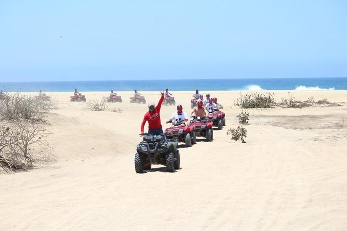 skupina ljudi, ki se vozijo s štirikolesniki na plaži