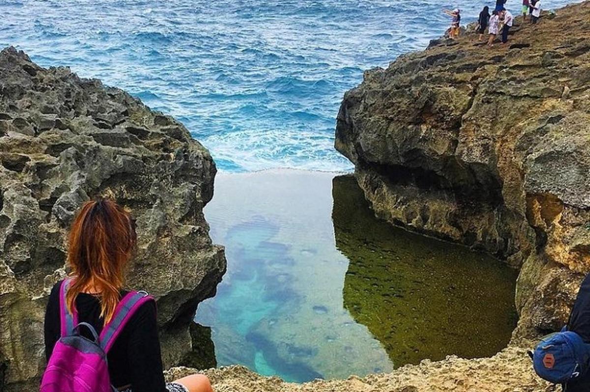 una donna seduta su una scogliera che guarda l'oceano