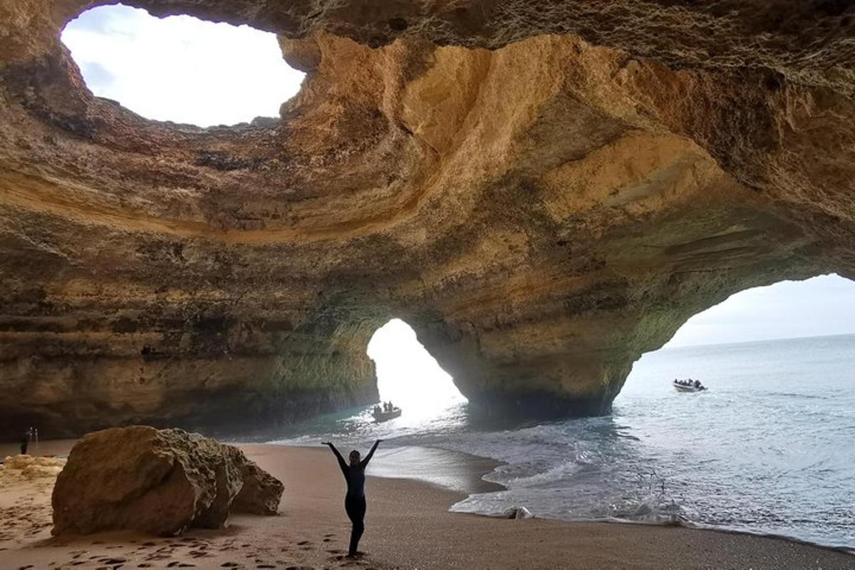 một người đứng trước một hang động trên bãi biển
