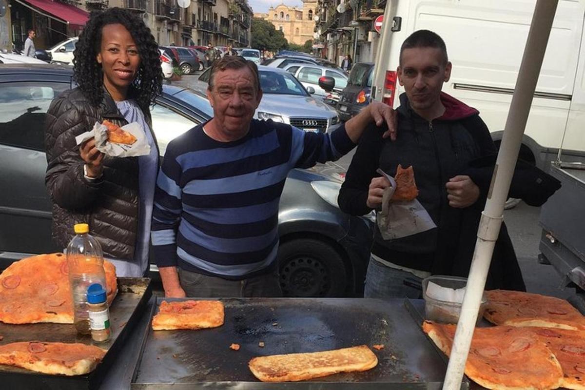 un uomo e due donne in piedi accanto a una griglia con la pizza