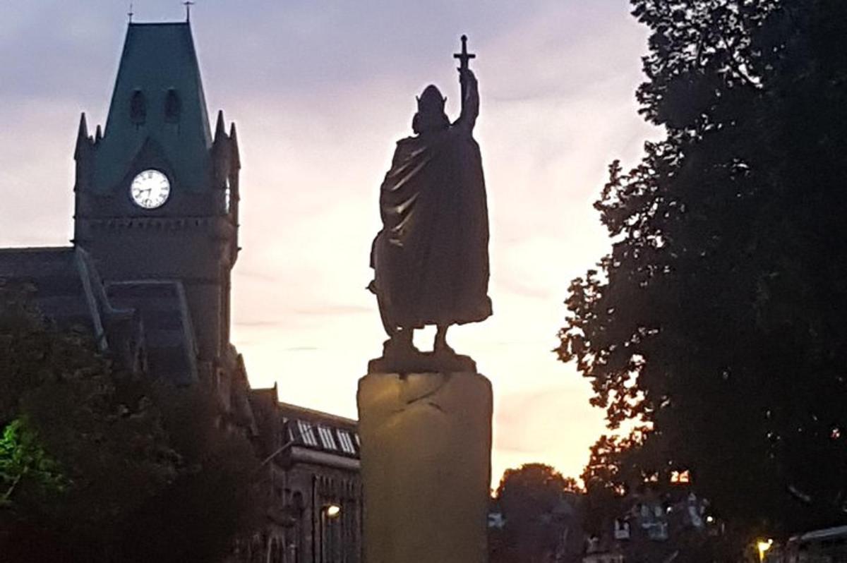 eine Statue vor einem Gebäude mit einem Uhrenturm