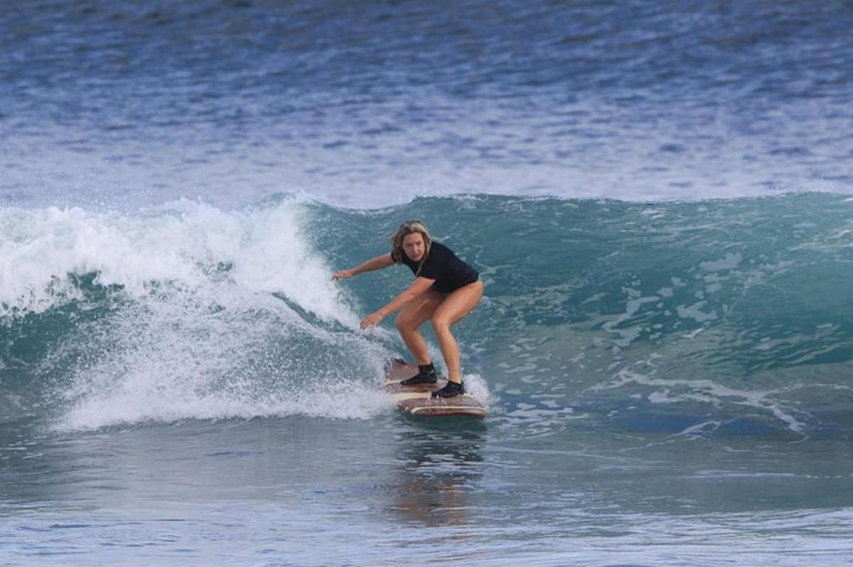 uma mulher pegando uma onda em uma prancha de surfe no oceano