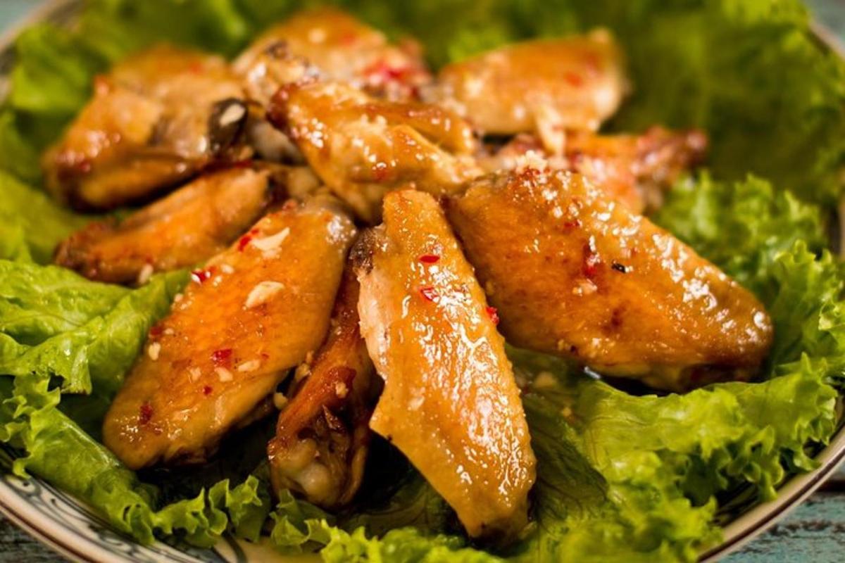 một đĩa thức ăn với cánh gà và rau diếp