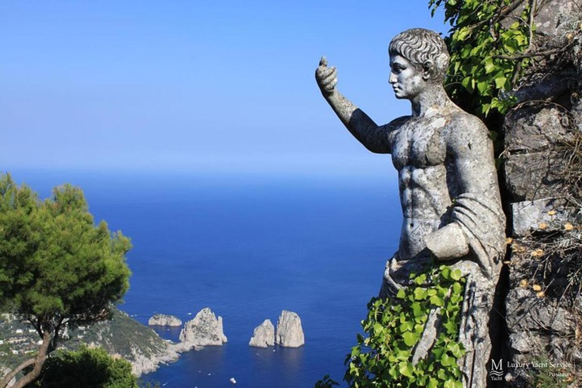 una estàtua d'un nen dret en un penya-segat amb vistes a l'oceà