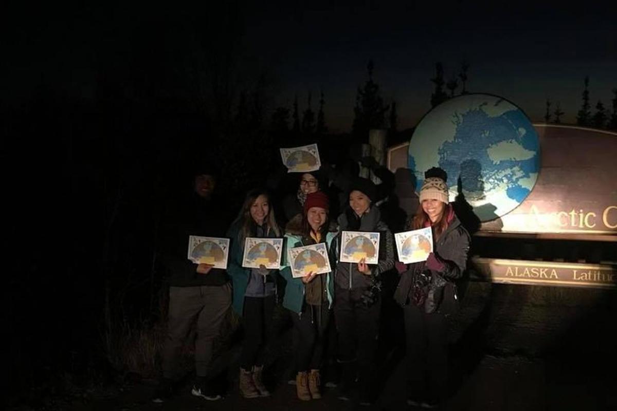 Un grupo de personas sosteniendo fotografías frente a un globo terráqueo.