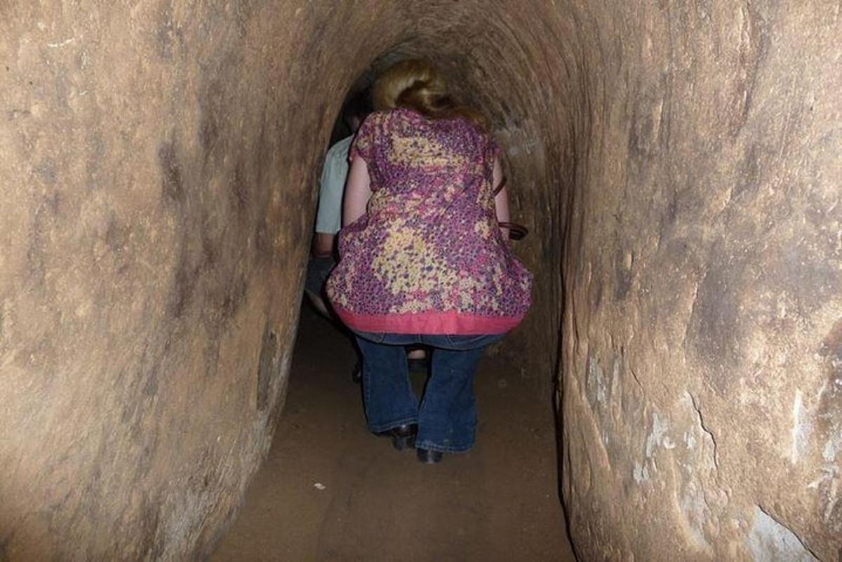 a woman is walking through a dark tunnel