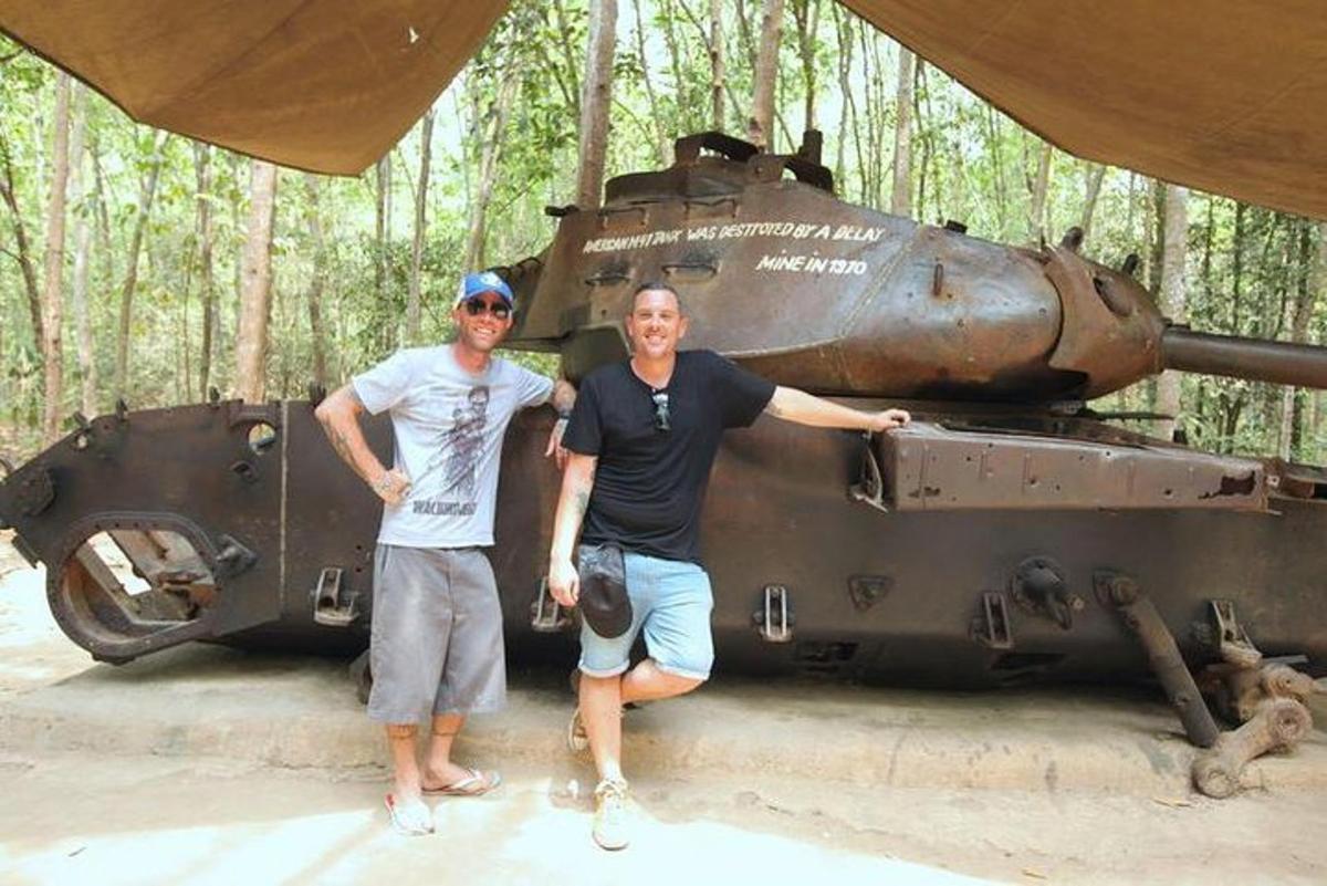 two men standing in front of an old tank