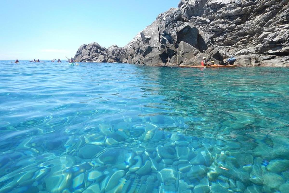 eine Gruppe von Menschen, die im Wasser in der Nähe einer Klippe schwimmen