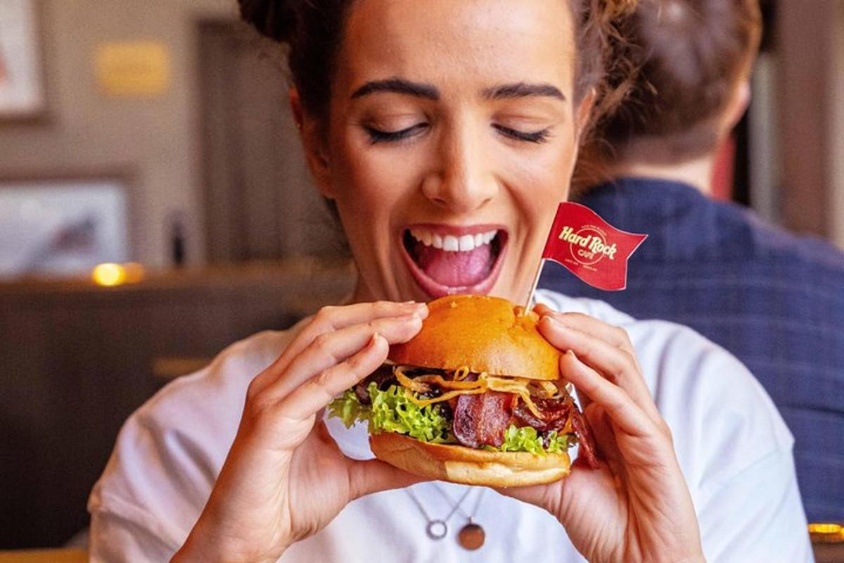 eine Frau, die mit ihren Händen ein großes Sandwich isst