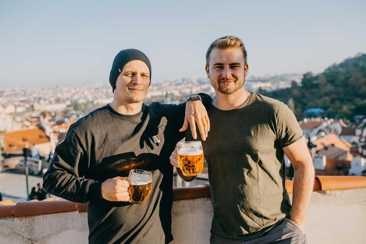 Dos hombres sosteniendo vasos de cerveza de pie en una cornisa