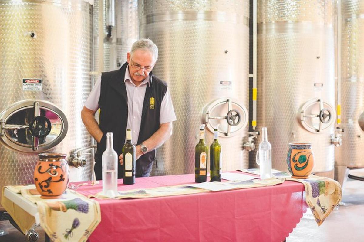 a man standing behind a table with bottles of wine