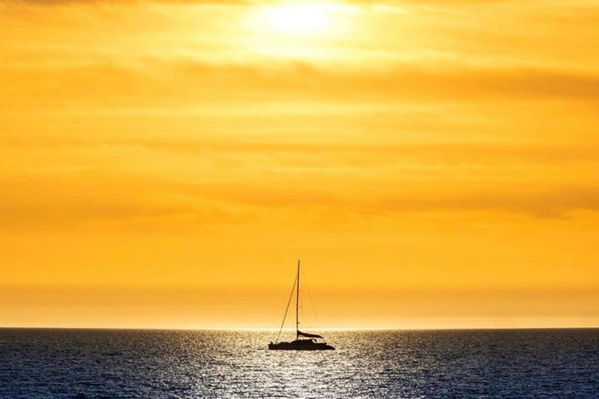 en seilbåt i havet under en oransje himmel