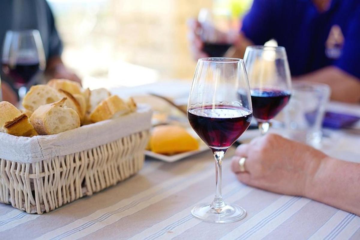uma mesa com duas taças de vinho e uma cesta de pão