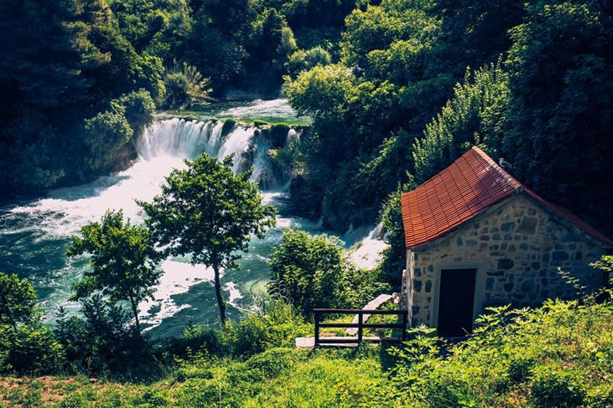 um pequeno edifício próximo a um rio com uma cachoeira