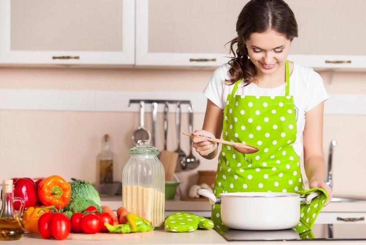 a woman in a kitchen stirring a pot with a wooden spoon