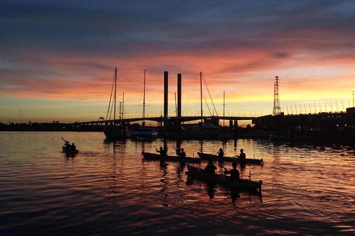 un grup de persones en barques a l'aigua a la posta de sol
