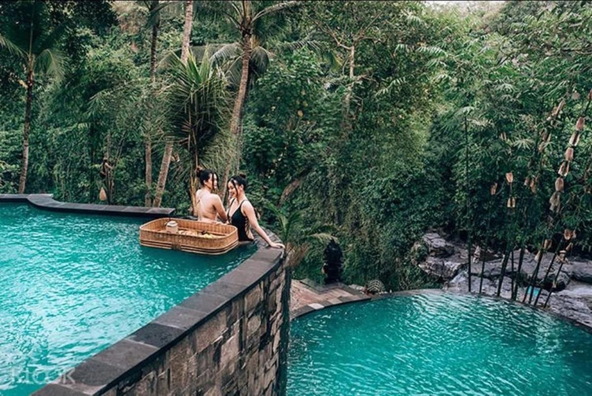 two people sitting on a wall next to a pool of water