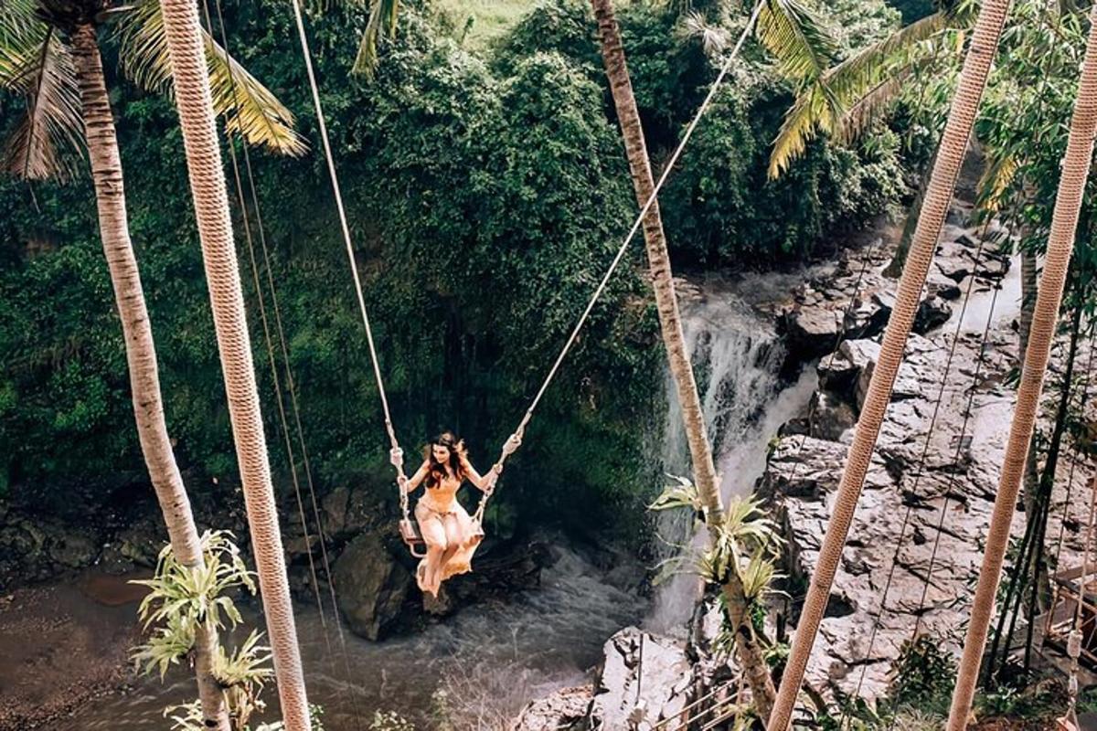 a woman sitting on a swing over a waterfall
