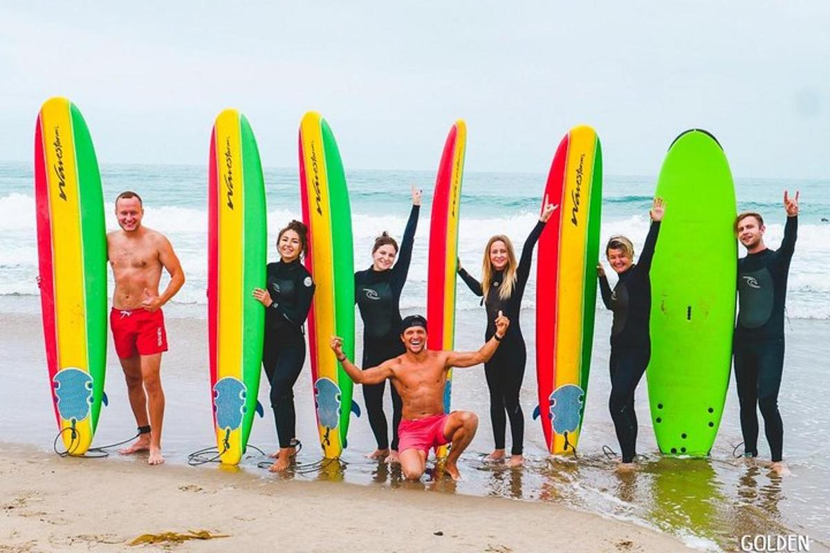 un grup de persones dempeus a la platja amb taules de surf