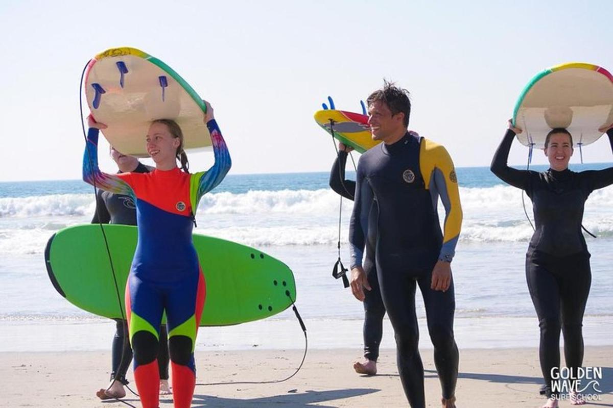 un gruppo di persone che camminano sulla spiaggia con le tavole da surf