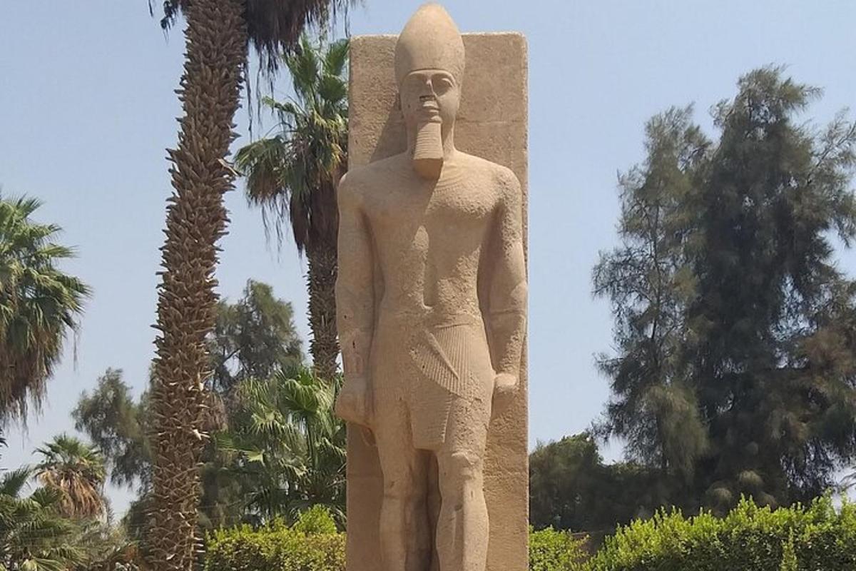 a statue of a man standing next to palm trees
