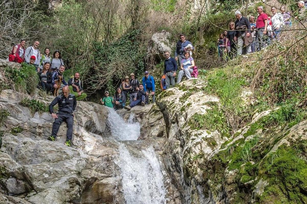 um grupo de pessoas sentadas nas rochas perto de uma cachoeira