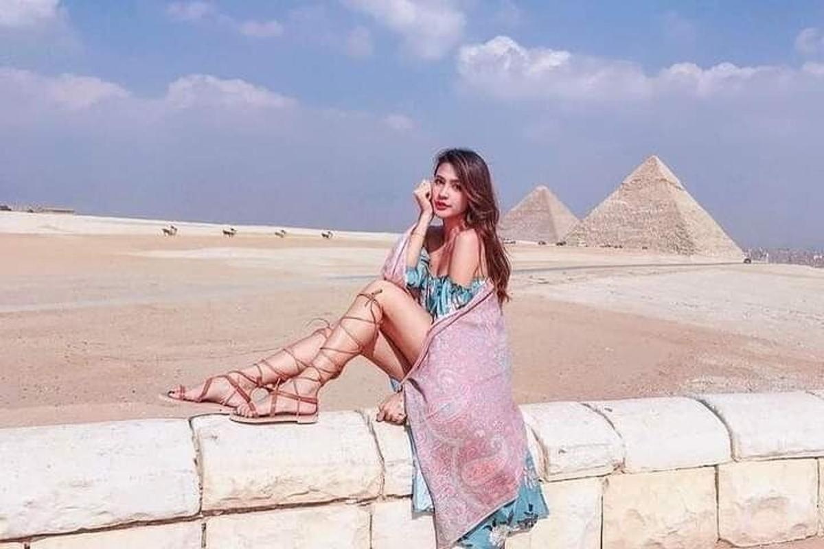 žena v šatech sedící na zdi poblíž pyramid