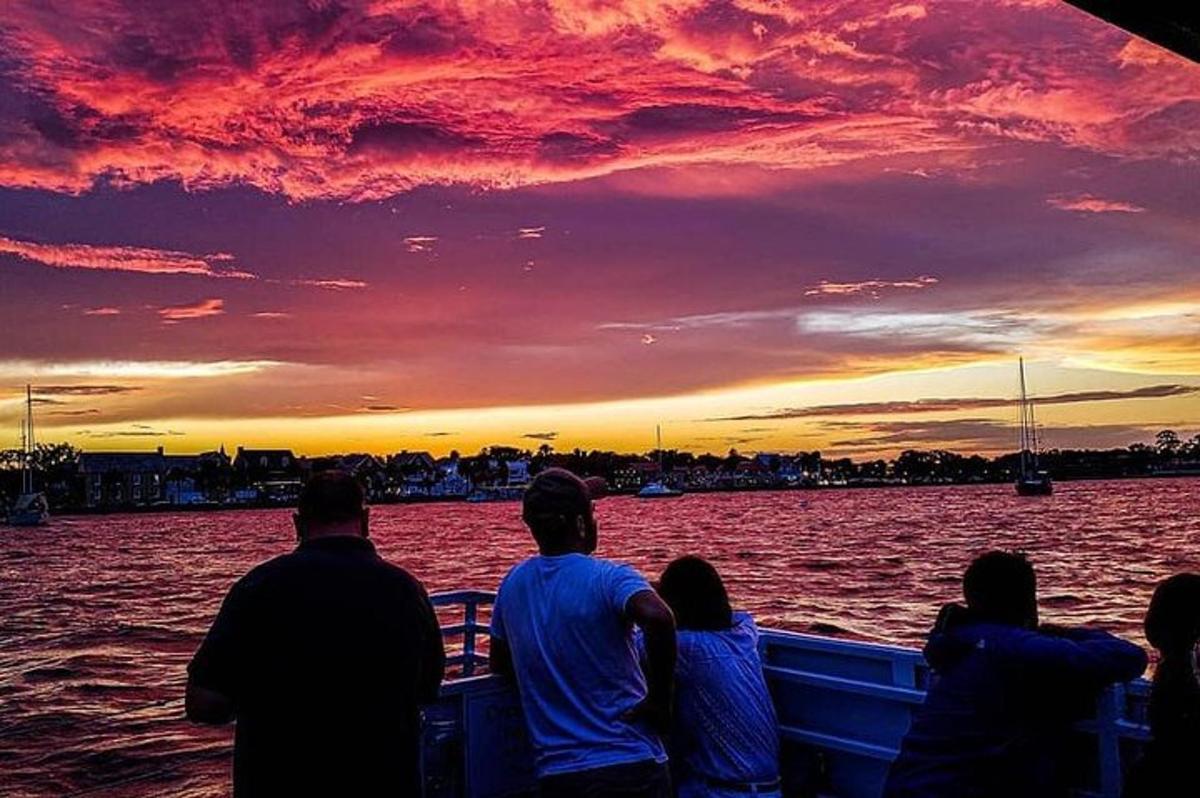 un gruppo di persone sedute su una barca al tramonto