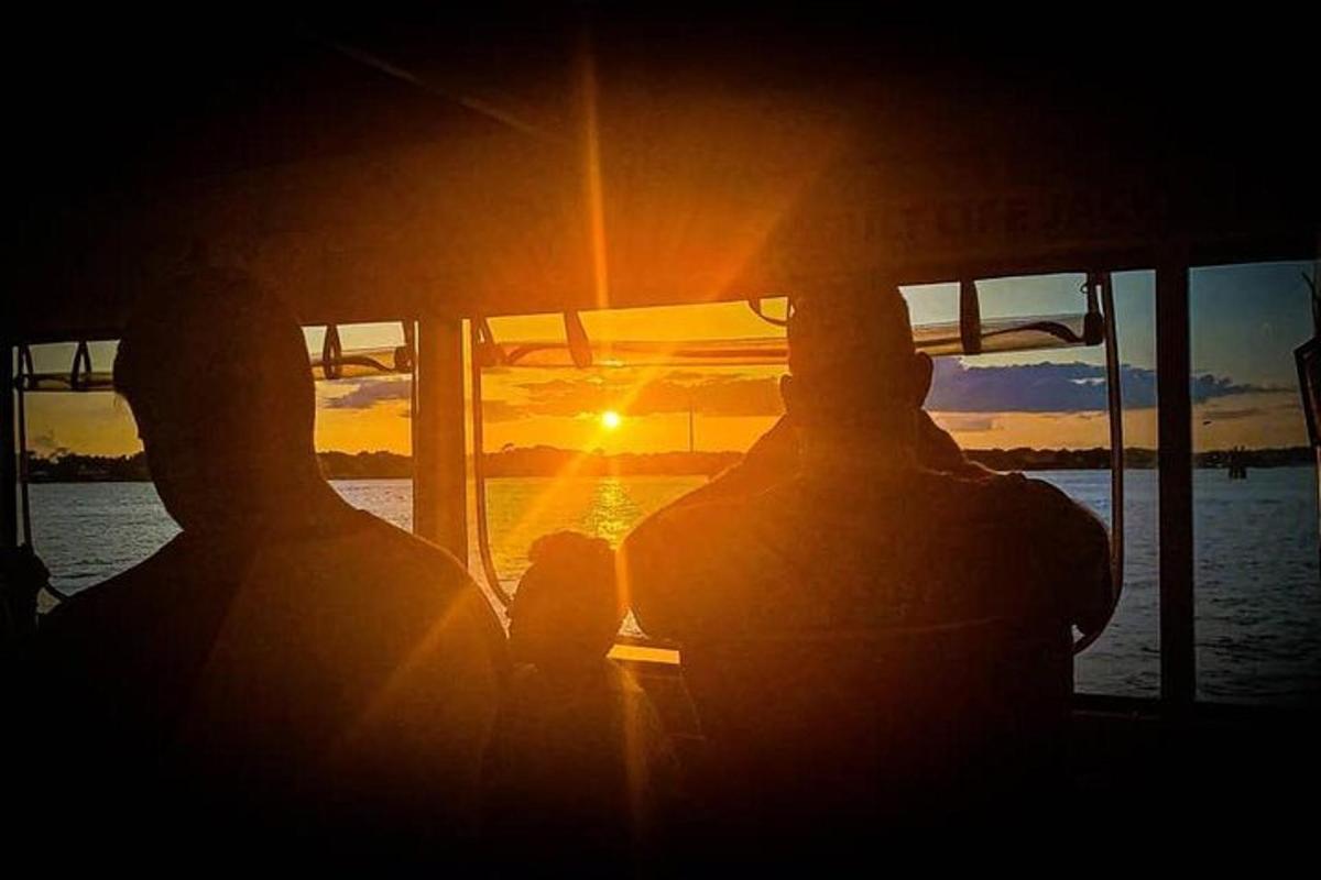 een groep mensen op een boot bij zonsondergang