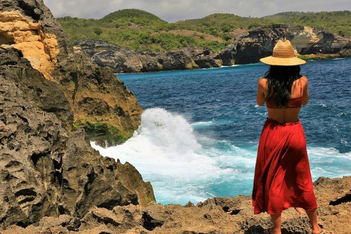 Una mujer con sombrero parada en las rocas cerca del agua.