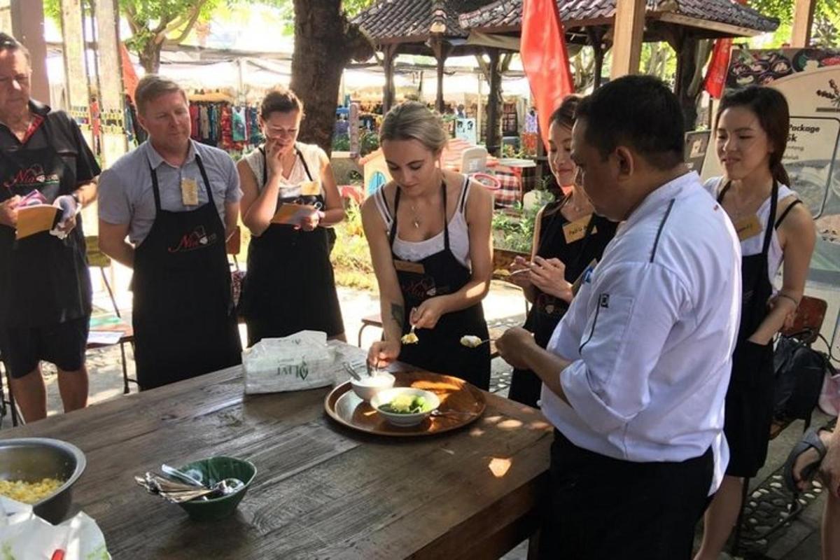 a group of people standing around a table with a man cutting a cake