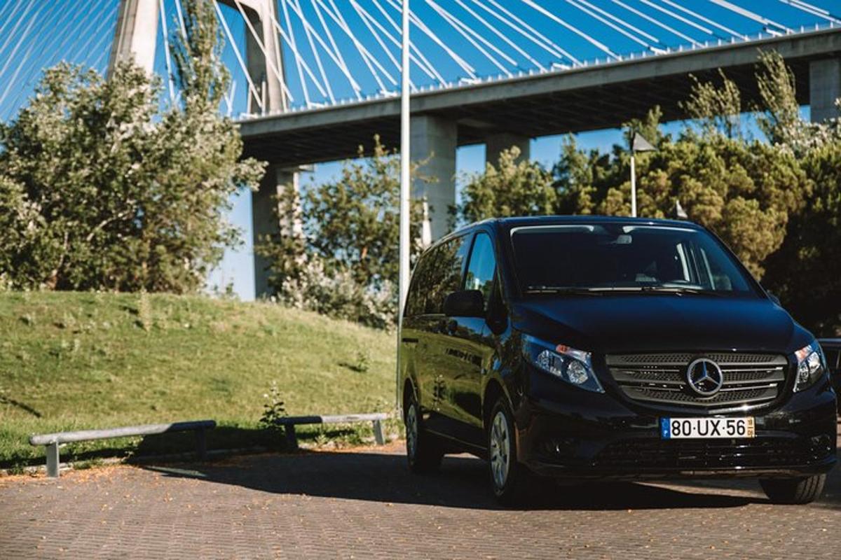 a black van parked on a road with a bridge in the background