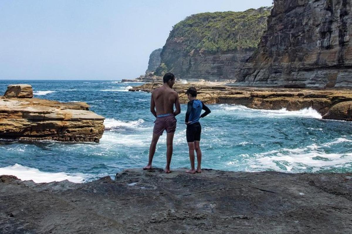 seorang pria dan seorang wanita berdiri di atas batu dekat laut