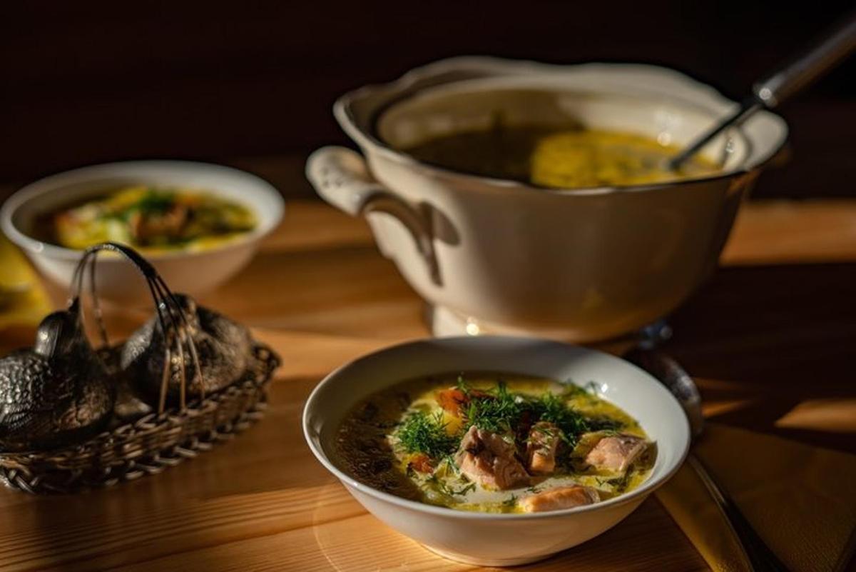 a wooden table with two bowls of soup and two cups