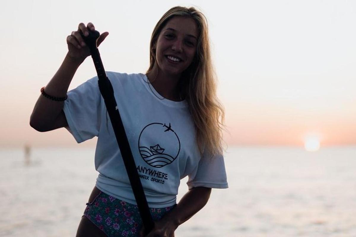 žena stojící na pláži a držící veslo