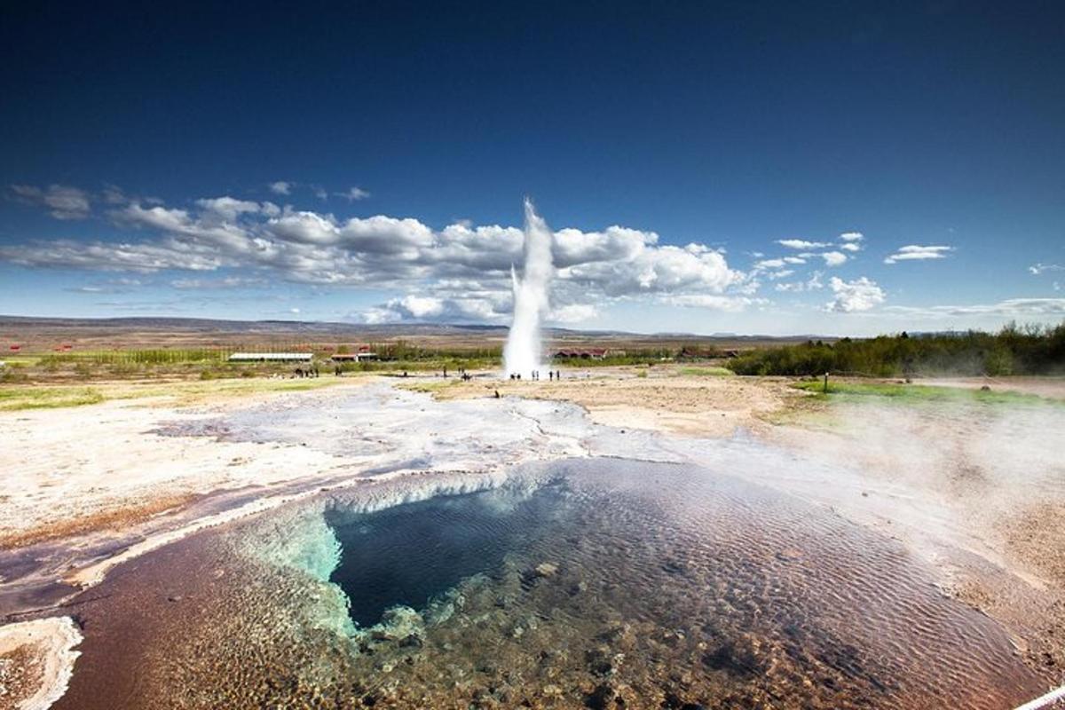 un geyser in mezzo a un campo con una pozza d'acqua