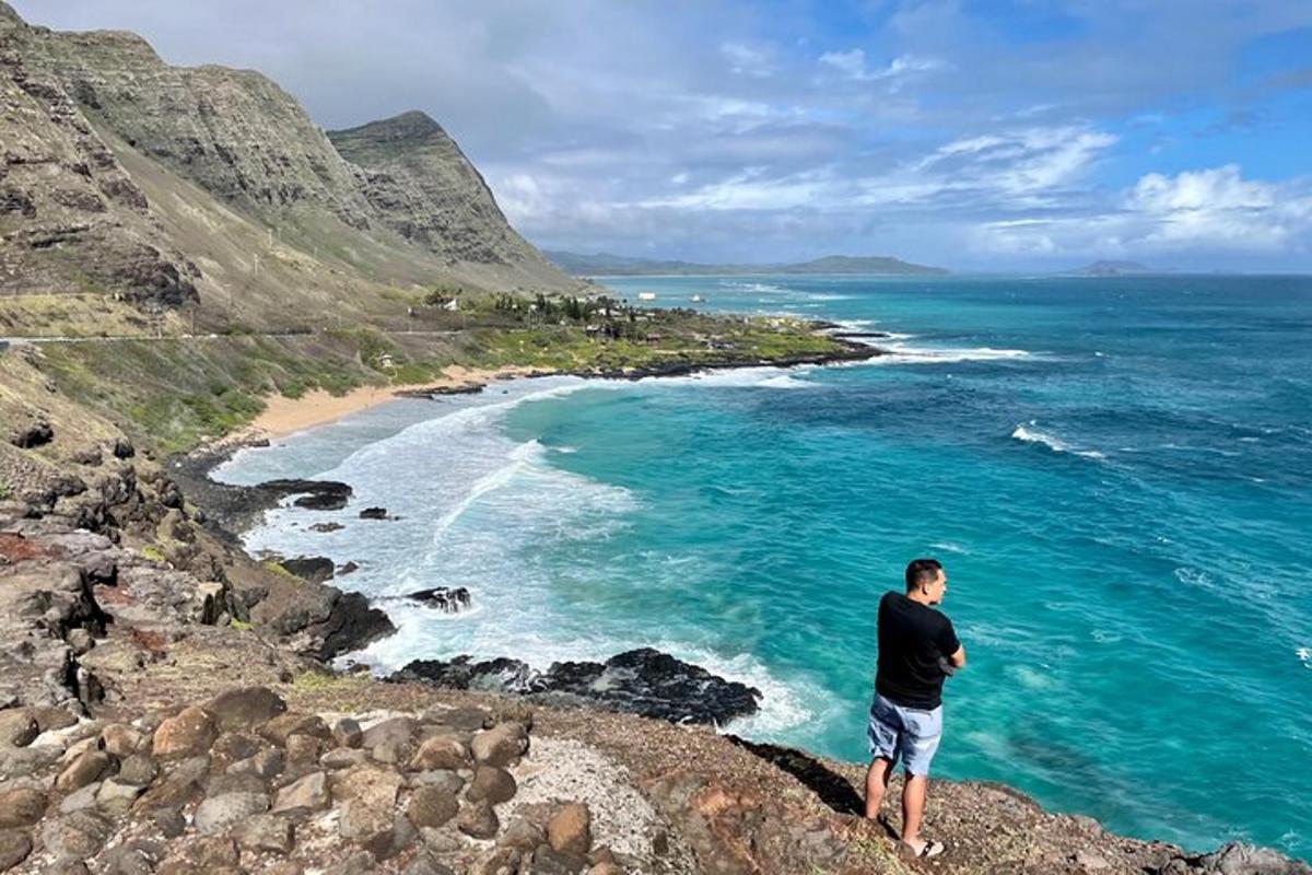 en mann som står på en klippe og ser på havet