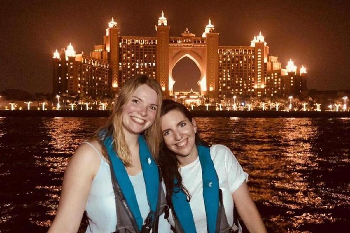two women on a boat in the water in front of a city