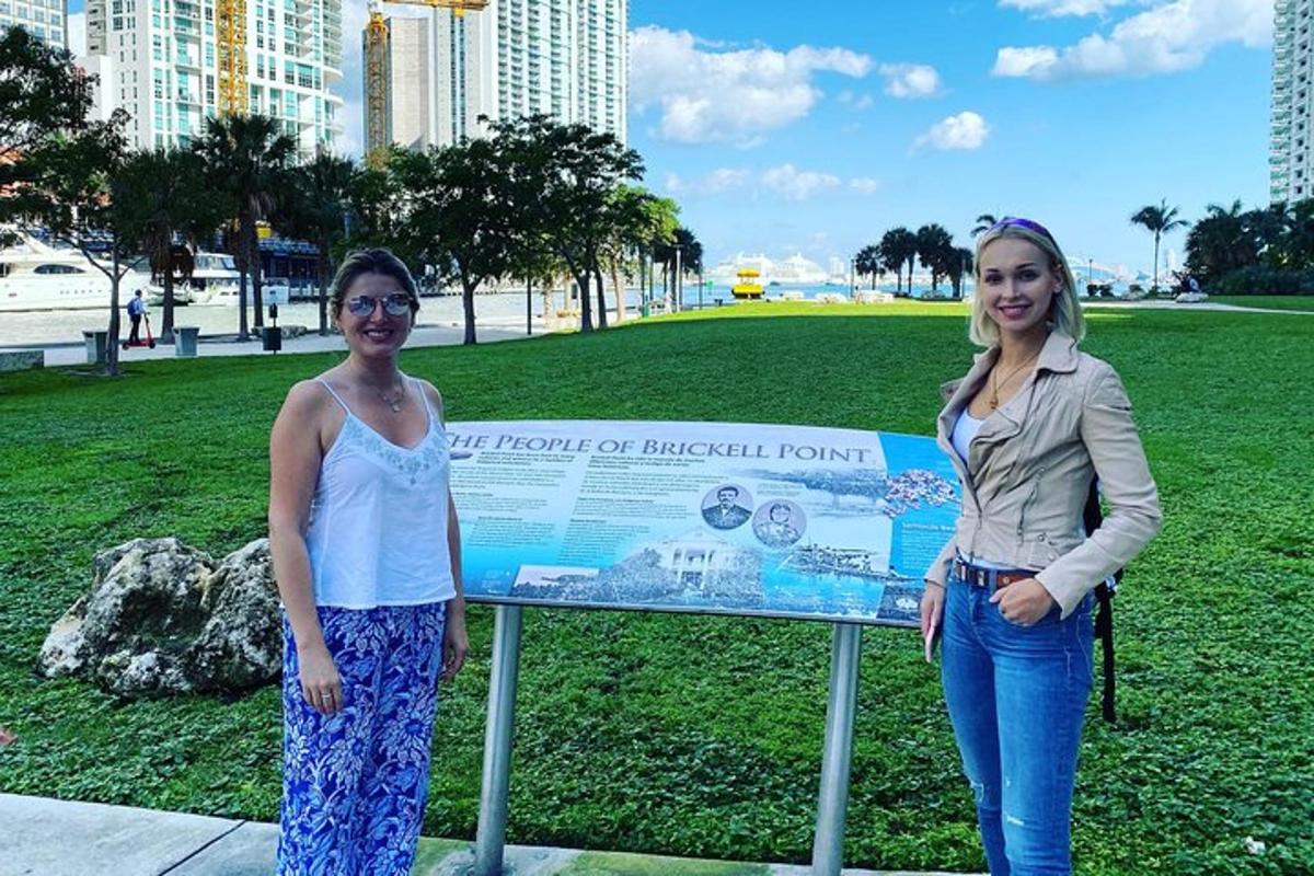 two women standing next to a sign in a park